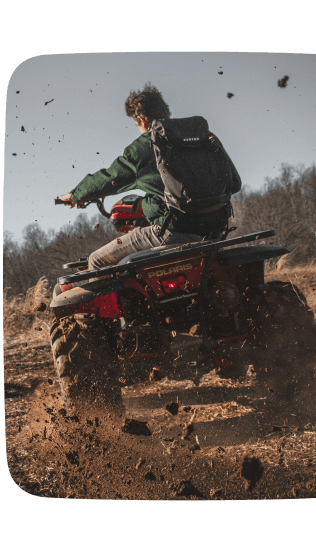 Personne conduisant un quad sur un chemin boueux, soulevant de la terre en roulant à vive allure.