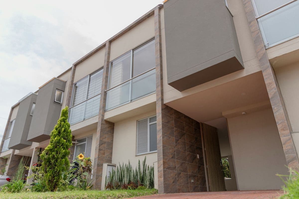 Alignement de maisons modernes à deux étages avec façades en pierre et béton, jardinet aménagé en premier plan.